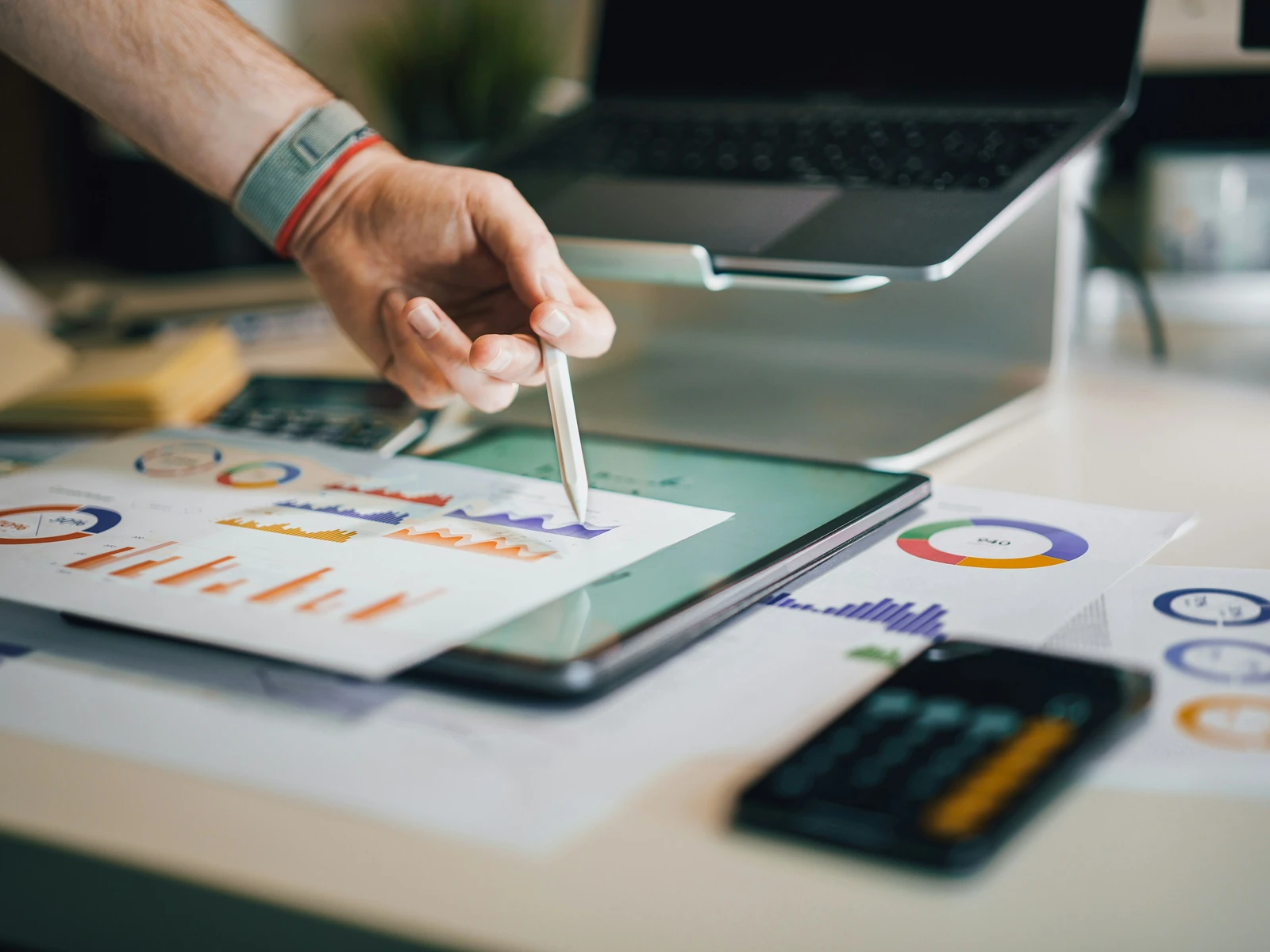A hand reviewing printed marketing performance charts